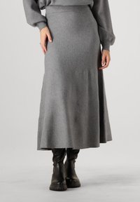 Grijze wollen midi-rok met een lichte A-lijnvorm, voorzien van een gladde textuur en een elastische tailleband, gedragen met kniehoge zwarte laarzen.