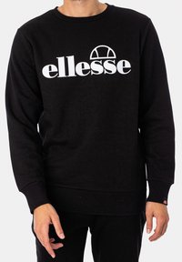 Schwarzer Pullover aus weichem Material mit einem weißen "ellesse"-Logo und einem Bogen-Design. Gerippte Bündchen und Saum. Schlichtes, minimalistisches Design.