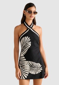 Rochie halter neagră cu modele albe de frunze, realizată dintr-un material texturat, cu detalii încrucișate la gât și o siluetă ajustată.
