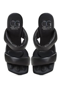 Sandales à glissière en cuir noir avec une tige rembourrée au design torsadé, un semelle intérieure texturée et un logo embossé sur la semelle.