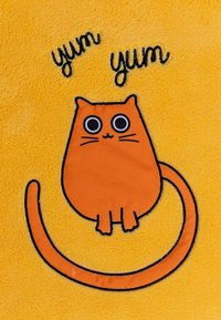 Grafik einer orangefarbenen Katze auf weichem gelbem Stoff, mit großen Augen und einem geschwungenen Schwanz, darüber der Text "yum yum" in schwarzem Stick.