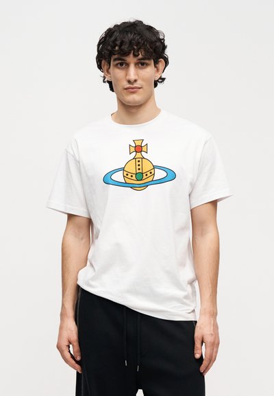 Λευκό βαμβακερό μπλουζάκι με γραφική εκτύπωση ενός κίτρινου σφαιριδίου με πράσινη πολύτιμη πέτρα, περιτριγυρισμένο από ένα μπλε δακτύλιο και με σταυρό στην κορυφή.