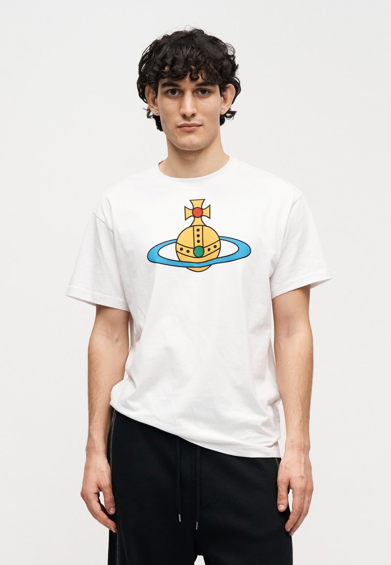 Hvid bomuld T-shirt med et grafisk tryk af en gul kugle med en grøn ædelsten, omgivet af en blå ring og toppet med et kors.