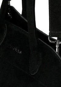 Černá semišová kabelka se dvěma uchy, zdobená jemným embosovaným logem a kovovými akcenty. Hladký povrch se švy.