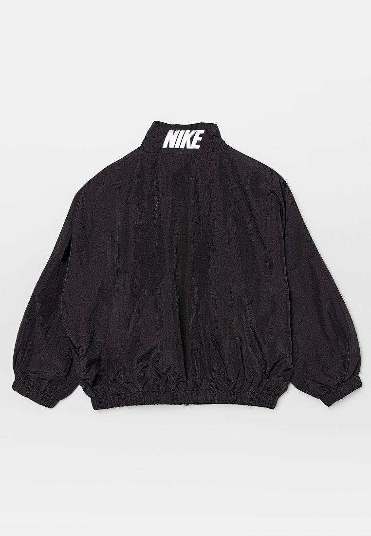Veste coupe-vent noire avec un col montant et des poignets élastiques. Présente un logo "NIKE" blanc dans le dos et un design ample.