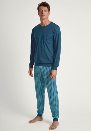 Long-sleeve blue shirt with a chest pocket, paired with patterned blue pants featuring a geometric design and elastic cuffs.