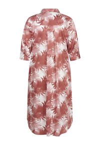 Langes, kragenloses Kleid mit einem Palmenblattmuster, das einen weißen Grund und rostfarbene Blätter aufweist, mit aufgerollten Ärmeln und einem entspannten Schnitt.