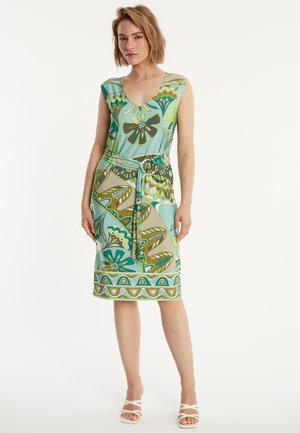 Mehrfarbiges Kleid mit V-Ausschnitt, kurzen Ärmeln und tailliertem Schnitt mit einem Gürtel. Der Stoff zeigt florale und Blattmuster in grünen und blauen Farbtönen.
