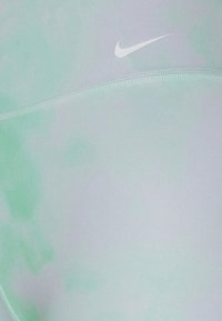 Legginsy Nike w jasnym miętowym zielonym i lawendowym gradiencie, wykonane z gładkiego, elastycznego materiału z małym białym logo i płaskimi szwami.