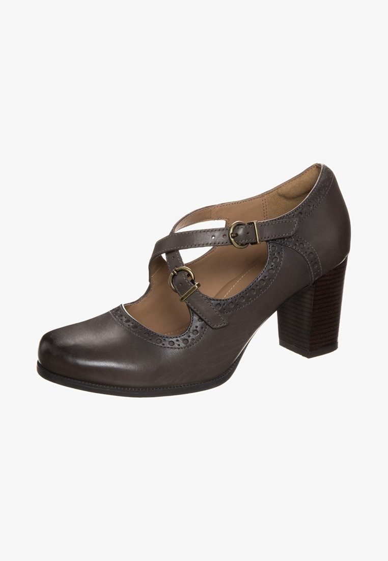Escarpin Mary Jane en cuir brun foncé avec deux brides réglables à boucles et des détails brogue sur les bords.