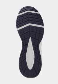 Sole of a black and white athletic shoe with grooved tread pattern for traction and flexibility.