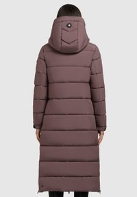 Palton lung tipat de culoare mauve, cu cusături orizontale, glugă și un detaliu cu buton în spate. Accente cu fermoar la tiv.