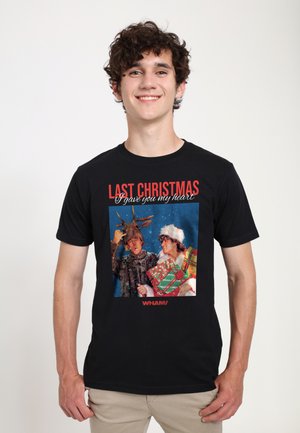 T-shirt en coton noir avec un imprimé graphique coloré représentant deux personnes, encadré par le texte : "DERNIER NOËL / Je t'ai donné mon cœur."