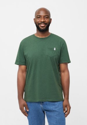 Groene, korte mouwen T-shirt van zachte katoen, met een zak aan de voorkant en een ronde halslijn, gecombineerd met blauwe jeans.