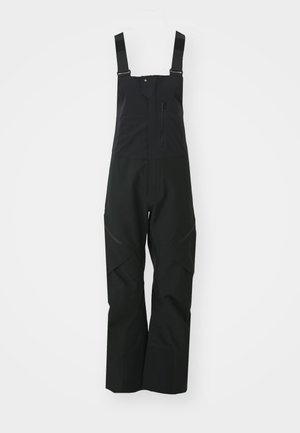 Sorte vandtætte bib-overalls har justerbare stropper, en lynlåslomme på brystet og forstærkede knæpaneler for holdbarhed.