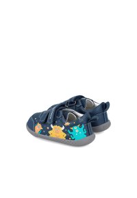 Zapatos de cuero azul con suelas grises, que presentan ilustraciones de monstruos en amarillo y verde. Incluyen tiras de Velcro para el cierre.