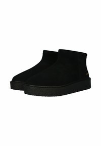 Botas de ante negras hasta el tobillo con una suela de plataforma negra texturizada, presentando una silueta suave y un diseño minimalista. Detalle de marca dorado en el lateral.
