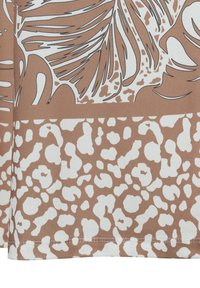 Brown and white fabric with abstract leaf and spotted animal print patterns, showing stitched hem edge.