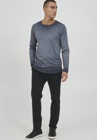 Langermet marineblå T-skjorte med en subtil gradient, rund hals, parret med svarte bukser og svarte sneakers. Flat, jevn tekstur.