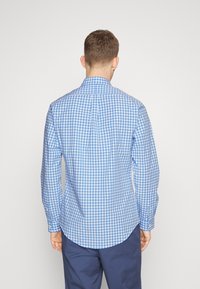 Blå rutigt skjorta med långa ärmar, knapp-down krage och en rundad nederkant. Tyget har en strukturerad väv för extra djup.