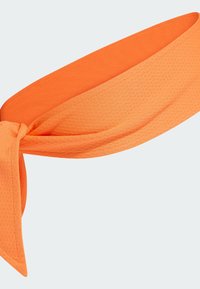 Diadema de tela naranja con un acabado texturizado. Presenta un detalle anudado en la parte frontal y extremos alargados para versatilidad en el peinado.