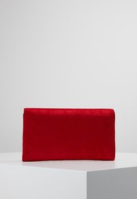 Punainen mokkainen clutch-laukku, jossa on tyylikäs suorakulmainen muoto, sileä pinta eikä näkyvää metalliosaa tai koristelua.