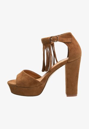 Sandalia de plataforma de ante marrón de tacón alto, con punta abierta, correa en el tobillo, cierre de hebilla y detalles de flecos en el talón.