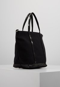 Borsa a tracolla nera con finitura testurizzata e dettagli in paillettes lucide su manici e base, caratterizzata da una forma strutturata.