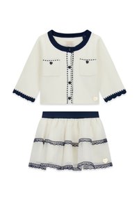 Cardigan blanc avec bordure marine, fermeture à boutons, deux poches frontales et bords festonnés, associé à une jupe en tulle à couches avec des accents en dentelle.