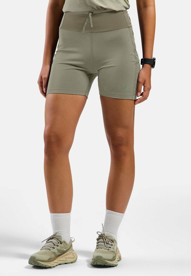 Shorts de sport ajustés en vert olive avec une taille haute et un cordon de serrage. Texture lisse avec un logo discret sur la jambe.