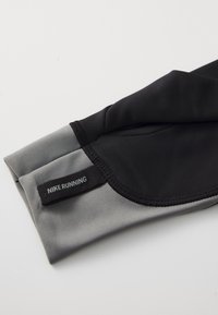 Mikb zm mocny rękaw biegowy Nike w czarno-szarym kolorze; gładka tekstura, dopasowany krój, posiada metkę z logo oraz kontrastowy blok kolorystyczny przy mankiecie.