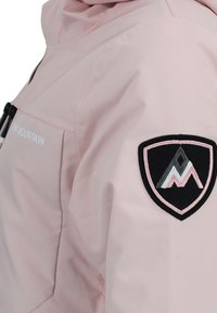 Lichtroze waterdichte jas met een capuchon, voorzien van een zwart en roze geborduurd logo op de mouw en een ritszak.