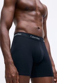 Férfi fekete boxer alsónadrág puha, ruganyos pamutkeverék anyagból. Széles derékpánttal rendelkezik, rajta fehér "Calvin Klein" logóval.
