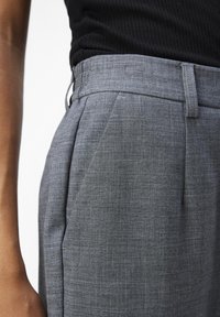 Graue maßgeschneiderte Hosen aus strukturiertem Stoff, mit Falten, einem glatten Taillenbund und einer eleganten, körpernahen Passform.