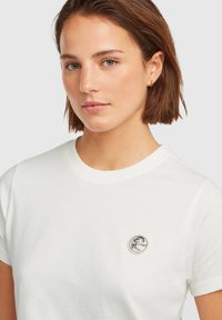 White cotton t-shirt featuring a round silver logo on the chest. The shirt has a classic crew neck and short sleeves.