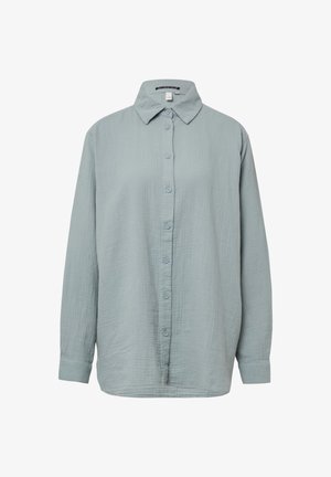 Šviesiai mėlynas, ilgomis rankovėmis mygtukų marškinys. Pagamintas iš minkštos, tekstūruotos medžiagos, turi standartinį apykaklę, su mygtukų uždarymu priekyje ir atsuktomis rankovėmis.