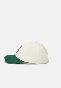 Baseball cap with a cream crown and a green brim. Features a stitched logo on the front and ventilation holes on the sides.