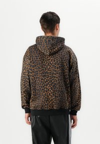 Felpa con cappuccio in tessuto leopardato con un motivo marrone e nero, caratterizzata da una vestibilità comoda e orli e polsini a costine.