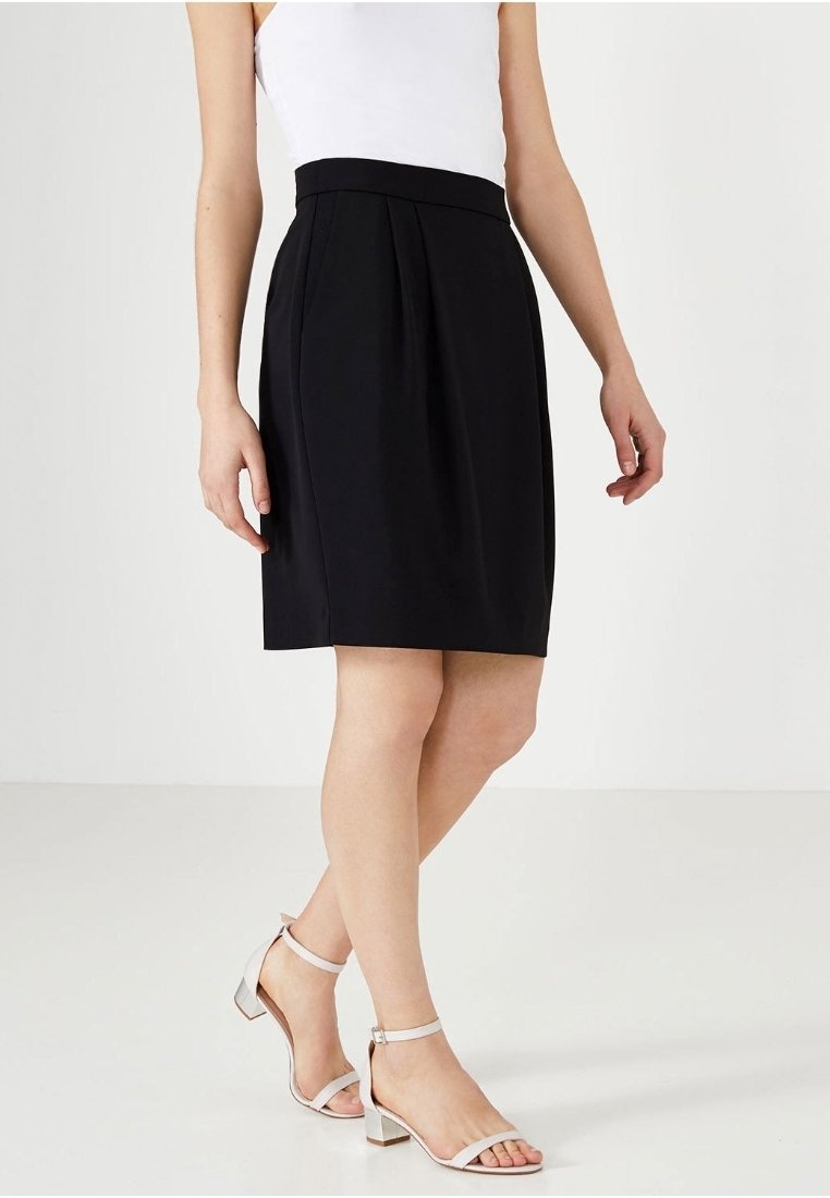 Černá sukně do áčka s plisováním v pase, vyrobená z hladké látky. Kombinována s světle zbarvenými sandály na podpatku se ramínky. Jednoduchý design, délka ke kolenům.