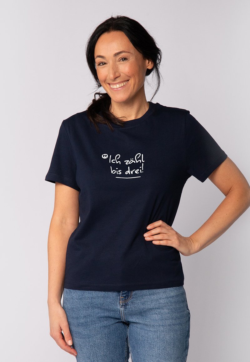 T-shirt en coton bleu marine à manches courtes, avec un design de texte imprimé blanc qui dit "Ich zähl bis drei !" sur le devant.