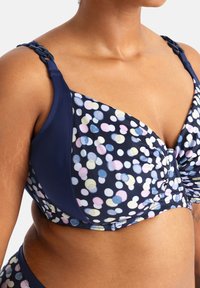 Námornícke modrý bikiny top s bielym, ružovým a modrým bodkovaným vzorom. Obsahuje textúrované ramienka s reťazcovým dizajnom a zhromaždené centrum.