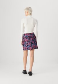 Turtleneck i ullblandning i vitt, tillsammans med en minikjol med blommönster i svart, rosa och blått, med en smidig textur och figuranpassad form.