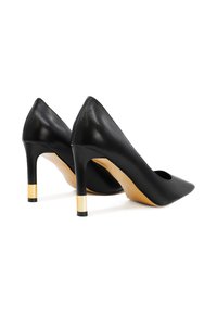 Scarpe nere in pelle con tacco alto e punta affilata, con tacco a stiletto accentato in oro e una texture liscia e lucida.