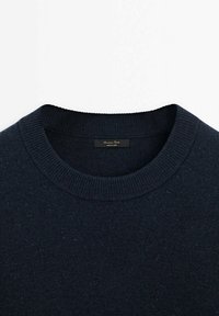 Dunkelblauer, gestrickter Pullover mit geripptem Rundhalsausschnitt. Verfügt über ein dezentes, strukturiertes Muster und ein Etikett am Hals. Weicher Stoffeinsatz.