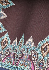 Tkanina w wzory z ciemnobrązowym tłem, z detalicznymi motywami paisley w kolorze turkusowym, kremowym i pomarańczowym wzdłuż brzegów.