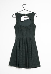 Vestido sin mangas de color verde oscuro con un patrón texturizado en forma de diamante, falda acampanada y un corte circular en la parte posterior. Etiqueta adjunta al escote.