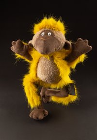 Stuffed monkey toy with brown body and yellow fuzzy accents. Features large eyes, a smiling face, and poses with arms raised.