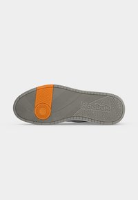 Γκρι σόλα παπουτσιού Reebok με υφή για καλύτερο κράτημα και πορτοκαλί κυκλικό και ορθογώνιο μοτίβο κοντά στην περιοχή της φτέρνας.