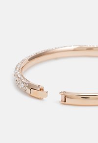Rosegold Armreif mit strukturiertem Band, verziert mit kleinen klaren Kristallen, und einem sicheren Verschluss an einem Ende.