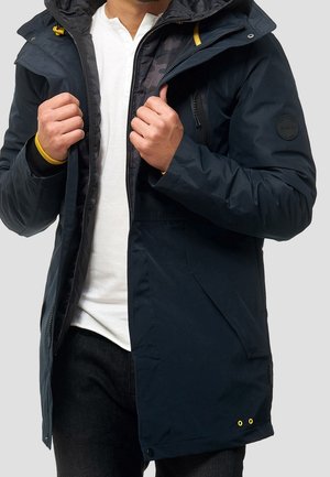 Navy insulated jacket with a zippered front, adjustable hood, yellow accents, and a textured inner lining, featuring a logo patch on the sleeve.